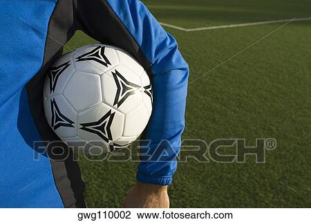 Mid section view of a man holding a soccer ball under his arm View Large Photo Image Stock Image - Mid section view of a man holding a soccer ball under his arm. Fotosearch
