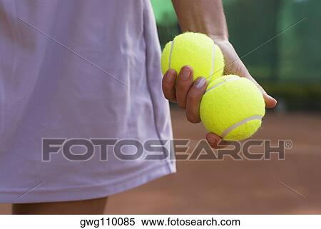 Mid section view of a young woman holding two tennis balls in her hand View Large Photo Image Stock Photography - Mid section view of a young woman holding two tennis balls in her hand. Fotosearch