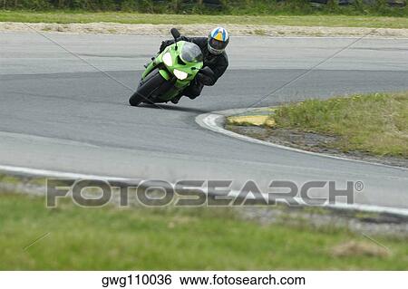 Person riding a motorcycle on a motor racing track View Large Photo Image Stock Photograph - Person riding a motorcycle on a motor racing track. Fotosearch