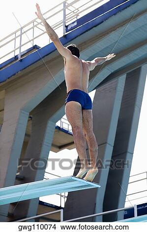 Picture - Rear view of a mid adult man taking start from a diving platform. Fotosearch