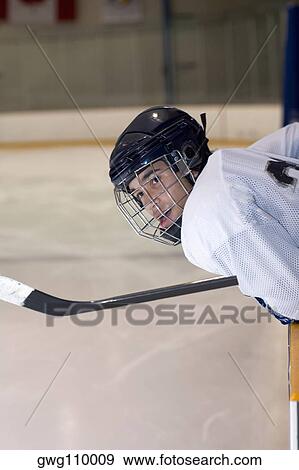 Side profile of an ice hockey player leaning over the railing of an ice rink View Large Photo Image Stock Photo - Side profile of an ice hockey player leaning over the railing of an ice rink. Fotosearch