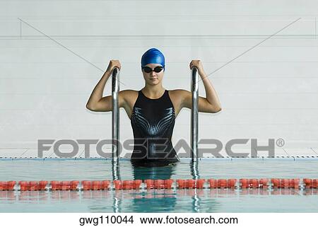 Picture - Teenage girl standing in a swimming pool and holding railings. Fotosearch