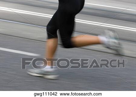 Stock Image - Low section view of a male athlete running on a running track. Fotosearch