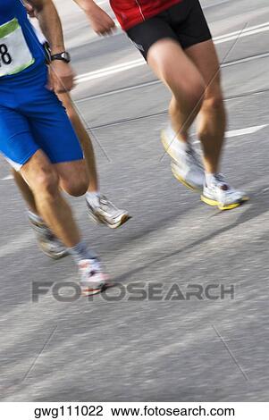 Low section view of three male athletes running on a running track View Large Photo Image Stock Image - Low section view of three male athletes running on a running track. Fotosearch