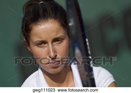 Portrait of a young woman holding a tennis racket View Large Photo Image Stock Image - Portrait of a young woman holding a tennis racket. Fotosearch