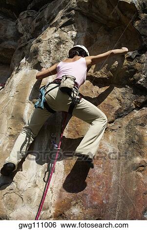 Rear view of a female rock climber scaling a rock face View Large Photo Image Stock Photograph - Rear view of a female rock climber scaling a rock face. Fotosearch