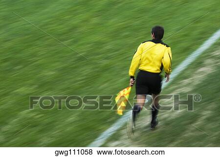 Stock Photo - Rear view of a referee running on a football pitch. Fotosearch