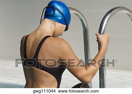 Picture - Side profile of a teenage girl stepping out from a swimming pool. Fotosearch