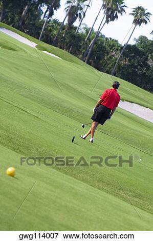 Rear view of a man holding a golf club in a golf course View Large Photo Image Stock Photo - Rear view of a man holding a golf club in a golf course. Fotosearch