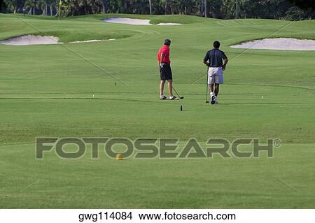 Two men playing golf in a golf course View Large Photo Image Picture - Two men playing golf in a golf course. Fotosearch