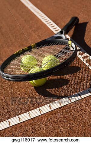 Stock Photo - Close-up of three tennis balls and a racket in a court. Fotosearch