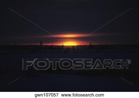 Stock Photo - Sunset over a frozen landscape, Churchill, Manitoba, Canada. Fotosearch