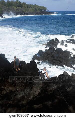 Stock Photo - Rear view of a two people standing on a cliff, Kehena Beach, Big Island, Hawaii Islands, USA. Fotosearch