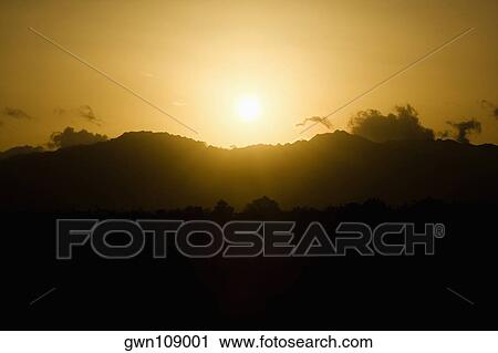 Stock Image - Sun over a mountain range, Nawiliwili Beach Park, Kauai, Hawaii Islands, USA. Fotosearch