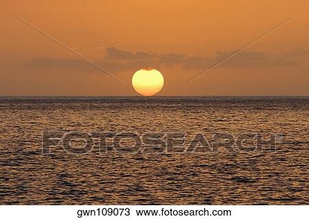 Stock Image - Sun over the sea, Pakini Nui Wind Project, South Point, Big Island, Hawaii Islands, USA. Fotosearch
