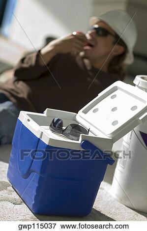 Stock Photo - Close-up of a cool box with a young man eating an apple in the background. Fotosearch
