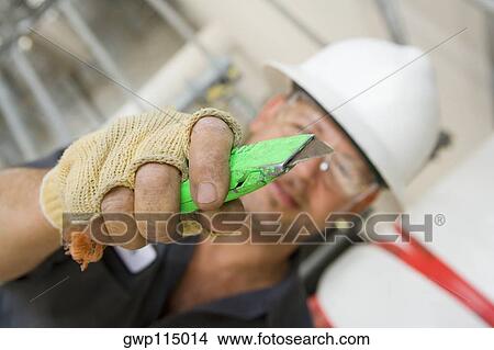 Close-up of a male construction worker holding a cutting tool View Large Photo Image Picture - Close-up of a male construction worker holding a cutting tool. Fotosearch