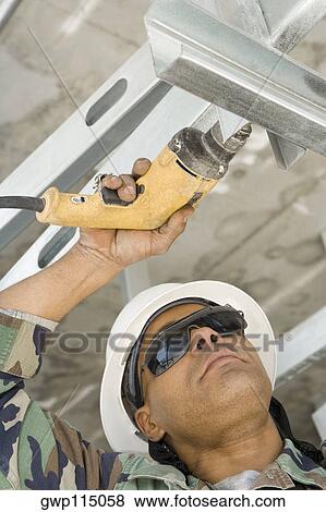 Stock Photo - Close-up of a male construction worker working with a hand drill. Fotosearch