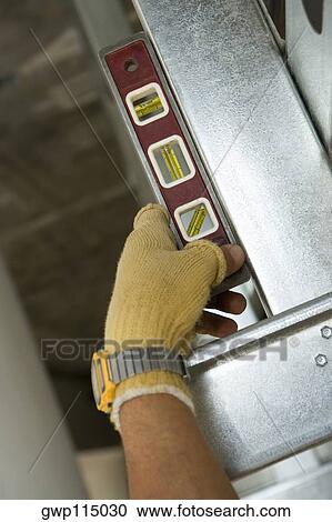Stock Image - Close-up of a person's hand using a spirit level. Fotosearch