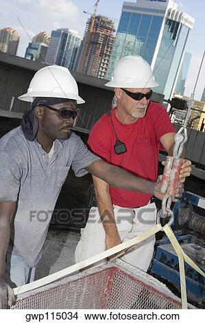Close-up of two male construction workers working at a construction site View Large Photo Image Picture - Close-up of two male construction workers working at a construction site. Fotosearch