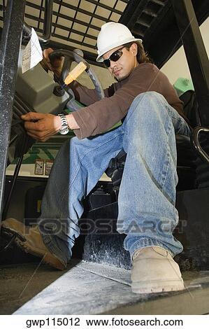 Stock Image - Low angle view of a young man operating a crane. Fotosearch