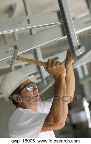Stock Photography - Mature man hitting with a hammer and fixing. Fotosearch