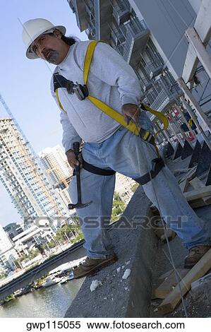 Mature man standing at the edge of a building and holding a hammer View Large Photo Image Stock Photography - Mature man standing at the edge of a building and holding a hammer. Fotosearch