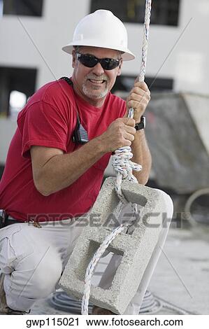 Mature man tightening a rope on a concrete block View Large Photo Image Stock Image - Mature man tightening a rope on a concrete block. Fotosearch