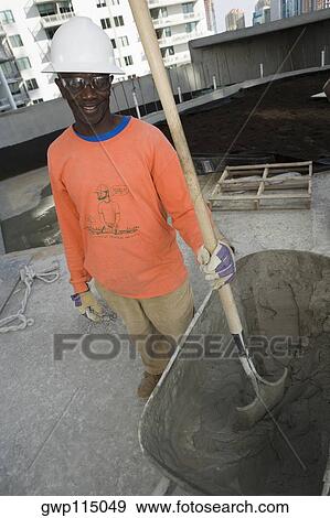 Stock Photo - Mid adult man standing and holding a shovel. Fotosearch