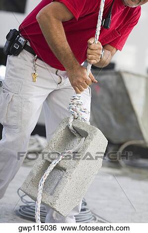 Stock Photograph - Mid section view of a male construction worker pulling a concrete block. Fotosearch