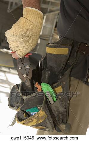 Mid section view of a man putting pliers into a tool belt View Large Photo Image Stock Photograph - Mid section view of a man putting pliers into a tool belt. Fotosearch