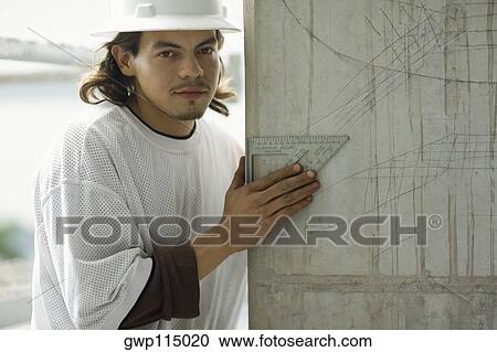 Stock Image - Portrait of a young man holding a set square. Fotosearch