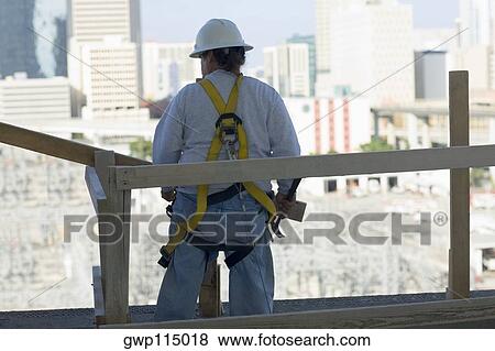 Rear view of a man standing and holding a hammer View Large Photo Image Stock Photo - Rear view of a man standing and holding a hammer. Fotosearch