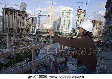 Side profile of a male construction worker working at a construction site View Large Photo Image Stock Photograph - Side profile of a male construction worker working at a construction site. Fotosearch