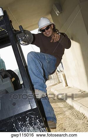 Young man climbing a machine and posing View Large Photo Image Stock Photograph - Young man climbing a machine and posing. Fotosearch