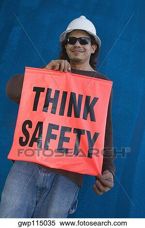 Stock Photography - Young man holding a banner of think safety. Fotosearch