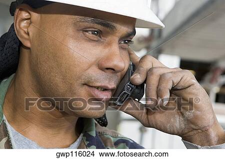 Close-up of a male construction worker talking on a mobile phone View Large Photo Image Picture - Close-up of a male construction worker talking on a mobile phone. Fotosearch