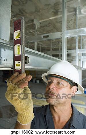 Stock Image - Close-up of a male construction worker using a spirit level. Fotosearch