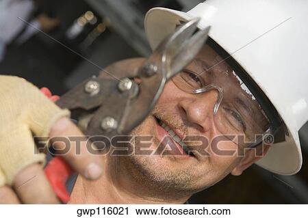 Stock Image - Close-up of a male construction worker holding a cutting tool. Fotosearch
