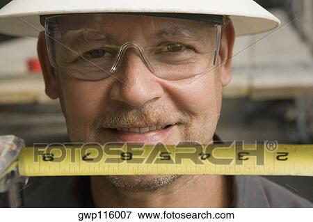 Stock Photo - Close-up of a male construction worker holding a tape measure. Fotosearch