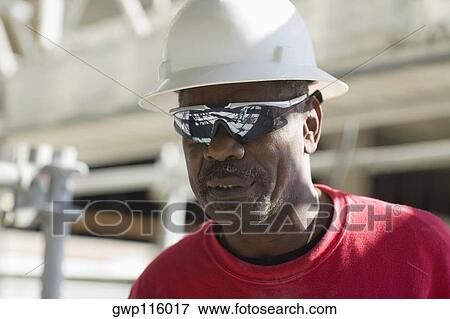 Stock Photo - Close-up of a male construction worker with a hardhat and a pair of sunglasses. Fotosearch