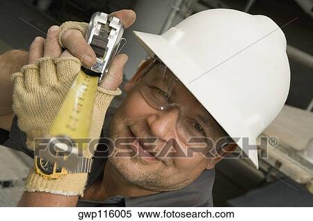 Close-up of a male construction worker holding a tape measure View Large Photo Image Stock Photography - Close-up of a male construction worker holding a tape measure. Fotosearch