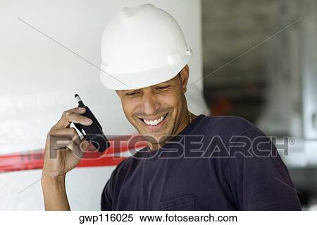 Close-up of a male construction worker talking on a walkie-talkie and smiling View Large Photo Image Stock Photography - Close-up of a male construction worker talking on a walkie-talkie and smiling. Fotosearch