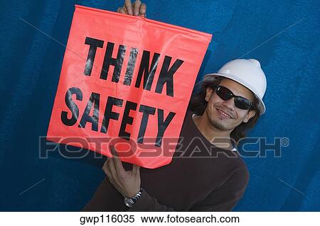 Close-up of a male construction worker smiling and holding a warning sign View Large Photo Image Stock Photography - Close-up of a male construction worker smiling and holding a warning sign. Fotosearch