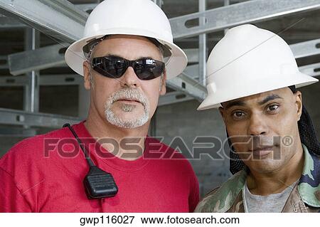 Stock Photo - Close-up of two male construction workers at a construction site. Fotosearch