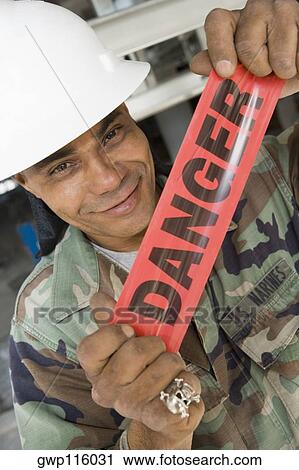 Portrait of a male construction worker holding a cordon tape and smirking View Large Photo Image Stock Image - Portrait of a male construction worker holding a cordon tape and smirking. Fotosearch