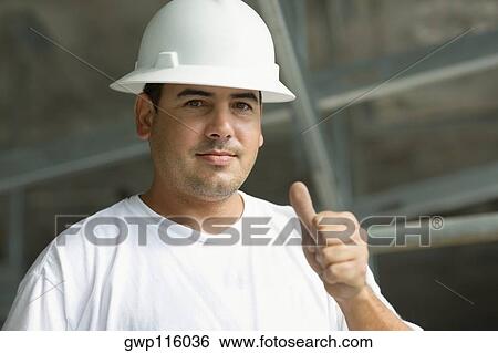 Stock Photograph - Portrait of a male construction worker showing a thumbs up sign. Fotosearch