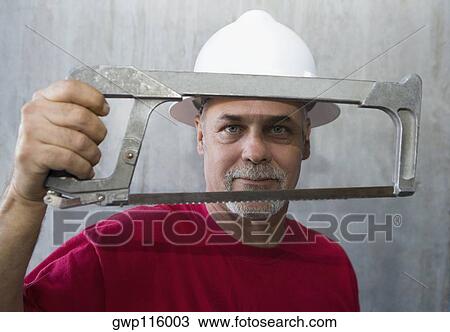 Stock Image - Portrait of a mature man holding a coping saw. Fotosearch