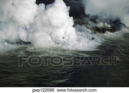 Stock Photograph - Steam rises from lava flowing into the sea, Hawaii. Fotosearch