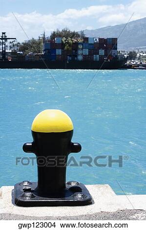 Close-up of a bollard with cargo containers in the background at a commercial dock View Large Photo Image Picture - Close-up of a bollard with cargo containers in the background at a commercial dock. Fotosearch